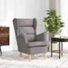 A grey fabric armchair is shown in a room with a wooden dresser and a plant. Náhľad obrázku produktu