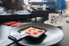 Auf einem schwarzen Teller steht ein ausziehbares Raclette-Pfännchen von Unold mit geschmolzenem Käs Produktbild-Vorschau