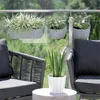 A balcony setting with chairs, a table, and planters on a glass railing. Podgląd zdjęcia produktu
