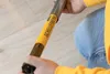 A person is holding a part of a product with yellow and black labeling. Produktbild-Vorschau