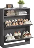 A grey shoe cabinet with multiple shelves and flip-down doors, filled with various shoes. A small plant sits on top of the cabinet. Produktbild-Vorschau