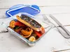 A glass food container with a meal inside, next to a blue lid and cutlery. Anteprima dell’immagine prodotto