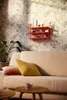 A living room scene with a sofa, pillows, a plant, and a shelf with decorative items. Produktbild-Vorschau
