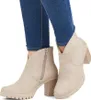 A pair of beige ankle boots worn by a person wearing blue jeans. Produktbild-Vorschau