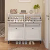 A white shoe cabinet with multiple compartments and drawers, placed in a hallway or entrance area. Náhľad obrázku produktu