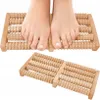 A pair of feet resting on a wooden foot massager. Produktbild-Vorschau