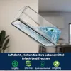 A clear plastic container filled with blue liquid and a green leaf, tilted to show its airtight seal. The background is a blurred interior scene. Produktbild-Vorschau