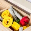 A close-up view of a wooden box filled with colorful toy tools, including screws, nuts, and bolts. Náhled obrázku produktu