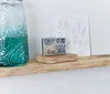 A weather station sits on a wooden shelf next to a decorative glass vase and a drawing. Náhled obrázku produktu
