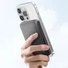 A hand holds a smartphone with a power bank attached to the back, against a light blue and white sky background. Podgląd zdjęcia produktu