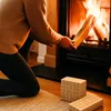 A person is adding a log to a fireplace. Produktbild-Vorschau