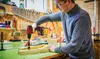A man is using a cordless drill in a workshop setting. Produktbild-Vorschau