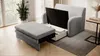 A gray sofa bed with its storage compartment open, next to a gray ottoman, in a well-lit room with large windows and a plant. Produktbild-Vorschau