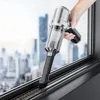A hand is using a handheld vacuum cleaner to clean a window sill. Produktbild-Vorschau