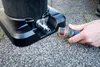 A hand is connecting a garden hose to a black base unit with a silver spigot. Produktbild-Vorschau