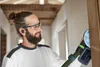 A man is sanding a wooden door frame with a power sander. Voir les images du produit