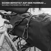 A close-up shot of black bungee cords with carabiner clips attached to a black bag secured to a bicycle seat post. Produktbild-Vorschau