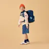 A young boy wearing a backpack and an orange beanie stands against a plain background. Podgląd zdjęcia produktu