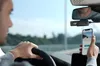 A person driving a car, holding a smartphone that displays the view from a dashcam. Náhľad obrázku produktu