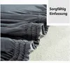 A close-up of a dark gray sofa cover with elasticated edges, next to a textured light gray surface. Produktbild-Vorschau