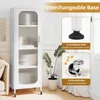 A white cabinet with glass doors is shown, with inset images highlighting its interchangeable base options: adjustable feet and universal wheels. Podgląd zdjęcia produktu