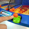 A close-up shot of a person's finger interacting with an electronic arcade basketball game. Produktbild-Vorschau