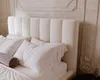 A close-up view of a cream-colored upholstered headboard and pillows on a bed. Náhled obrázku produktu