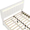 A close-up view of a white upholstered bed frame with a tufted headboard and integrated LED lighting, showing the wooden slat support system for the mattress. Produktbild-Vorschau
