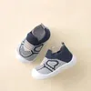 Paar blaue und hellgraue gestrickte Babyschuhe zum Laufenlernen mit weißen Sohlen, von oben gesehen Anteprima dell’immagine prodotto