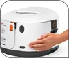 A hand is shown pressing a button on a white deep fryer. Produktbild-Vorschau