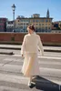 A woman walks across a street in front of buildings. Produktbild-Vorschau