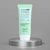 A green tube of sunscreen sits on a silver pedestal against a gray background. Náhled obrázku produktu