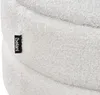 A close-up view of a white bouclé fabric surface with a black brand tag attached. Náhled obrázku produktu