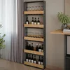 A tall, narrow wine rack with shelves for bottles and glasses, placed indoors next to a window with curtains and a table. Produktbild-Vorschau