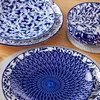 A close-up view of blue and white patterned ceramic plates and a bowl. Produktbild-Vorschau