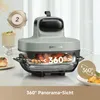 A modern kitchen appliance, likely an air fryer, is shown on a countertop with food inside and around it. Decorative elements like a cake and a small plate of food are also visible. Produktbild-Vorschau