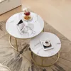 Two round coffee tables with marble-like tops and gold metal frames are placed on a rug in a living room setting. Voir les images du produit