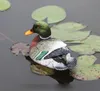 A realistic-looking duck decoy floats on water surrounded by lily pads. Produktbild-Vorschau