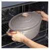 Hands placing a taupe cast iron pot into an oven. Náhľad obrázku produktu