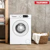 A white Telefunken washing machine is shown in a laundry room setting, with towels on a shelf to the left and a basket of laundry to the right. Produktbild-Vorschau