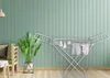 A laundry drying rack with clothes and a plant in a room with green paneled walls. Produktbild-Vorschau