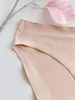 Beige nahtlose Unterwäsche mit glatter Stoffstruktur, gefaltet auf weißer Fläche neben einem rosa Deko-Blatt Produktbild-Vorschau