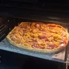 A pizza is being baked in an oven on a pizza stone. Podgląd zdjęcia produktu