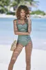 A woman posing on a beach in a green swimsuit. Produktbild-Vorschau