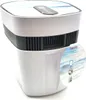 A white air purifier with a decorative top and a circular marketing label on its side. Produktbild-Vorschau