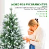 A woman holding a baby next to a decorated Christmas tree. Produktbild-Vorschau