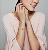 A woman wearing a pink top and a silver bracelet with a charm. Produktbild-Vorschau