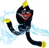 A black plush toy with yellow hands and feet, with water splashing around it. Produktbild-Vorschau