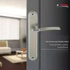 A door handle on a dark gray door, with a blurred interior scene visible through an open doorway. Produktbild-Vorschau
