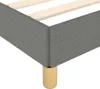 A close-up view of the corner of a grey fabric bed frame with wooden slats and a gold leg. Náhled obrázku produktu